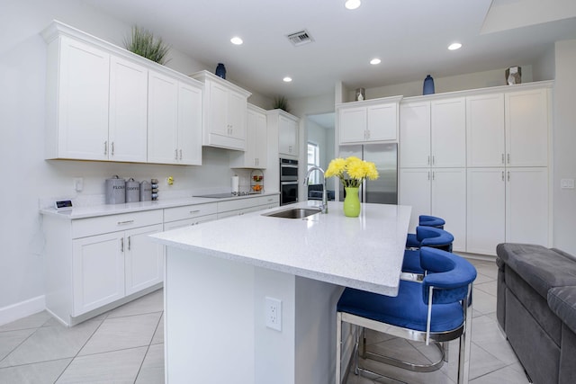 kitchen with white cabinetry, appliances with stainless steel finishes, an island with sink, and sink