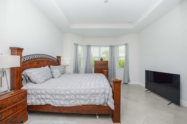 bedroom with light tile patterned floors and a raised ceiling