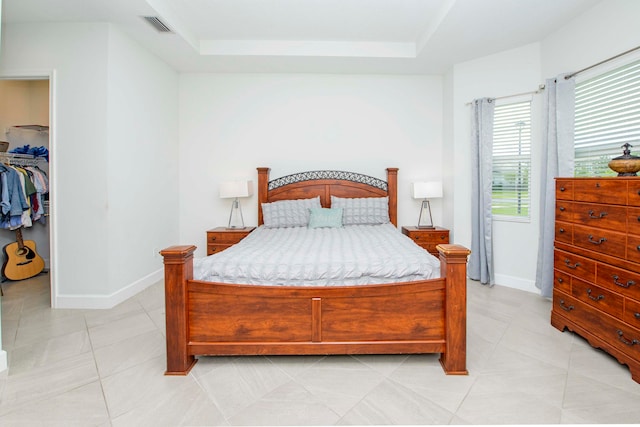 tiled bedroom with a closet and a raised ceiling