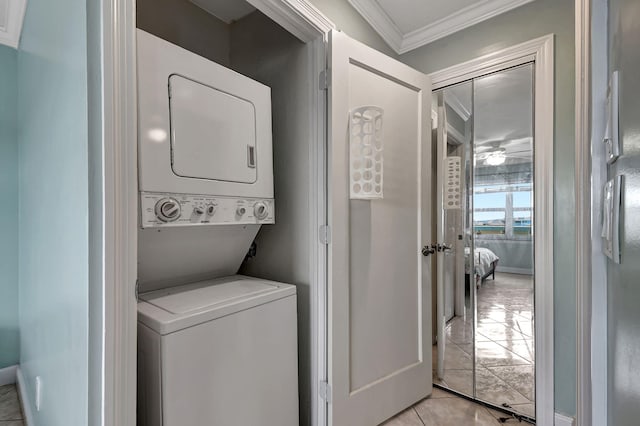 laundry area featuring stacked washer and dryer, ornamental molding, and light tile patterned flooring