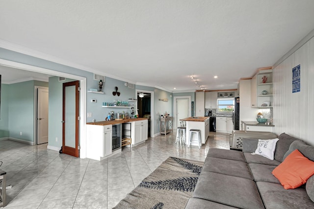 tiled living room featuring crown molding, indoor bar, and wine cooler