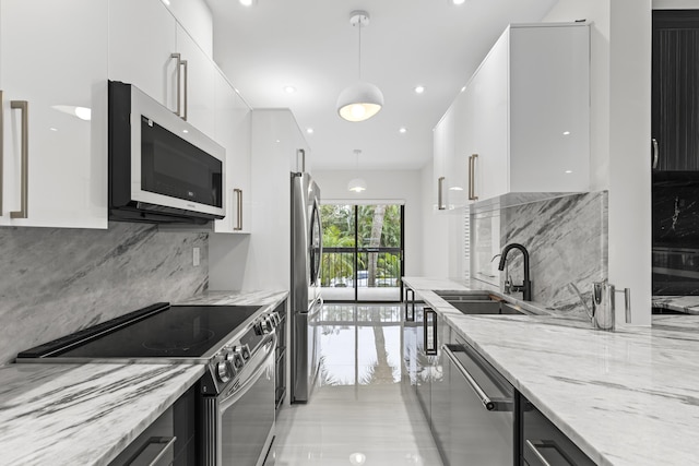 kitchen featuring stainless steel appliances, a sink, white cabinets, hanging light fixtures, and modern cabinets