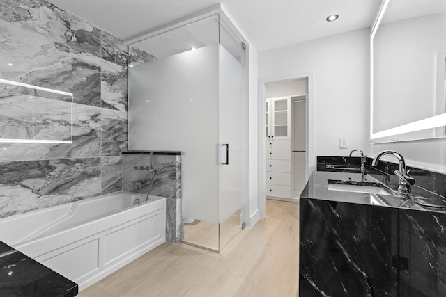 full bathroom featuring a marble finish shower, wood finished floors, a garden tub, a walk in closet, and a sink