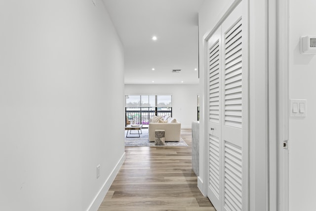 hallway featuring light wood-type flooring, visible vents, baseboards, and recessed lighting