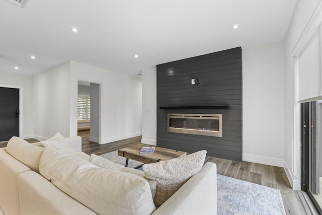 living area with recessed lighting, a fireplace, and wood finished floors