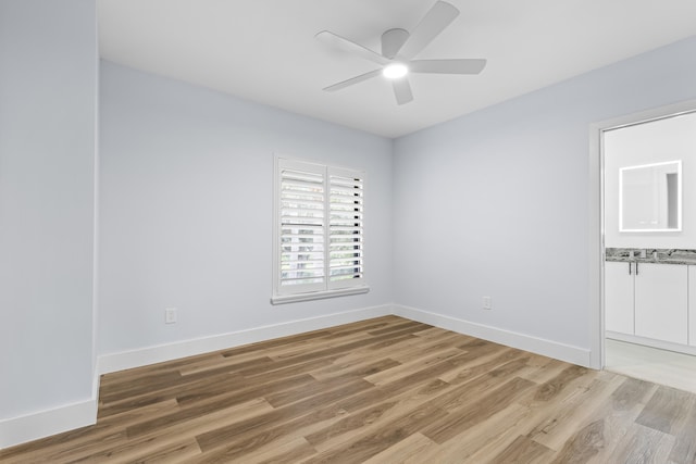 empty room featuring wood finished floors, a ceiling fan, and baseboards