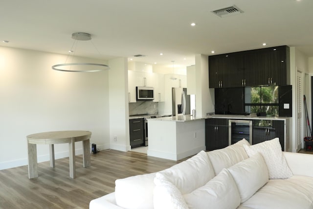 living area featuring recessed lighting, beverage cooler, visible vents, baseboards, and light wood-style floors