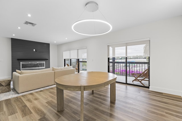 dining area featuring a large fireplace, visible vents, baseboards, and wood finished floors