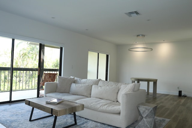 living area with dark wood-type flooring, visible vents, and baseboards