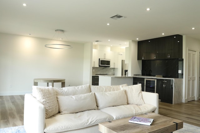 living area with light wood-style floors, wine cooler, visible vents, and recessed lighting