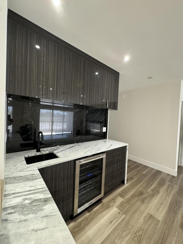 kitchen with light stone counters, light wood-style floors, a sink, modern cabinets, and beverage cooler