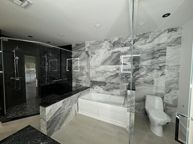 bathroom with a stall shower, visible vents, toilet, a garden tub, and tile walls