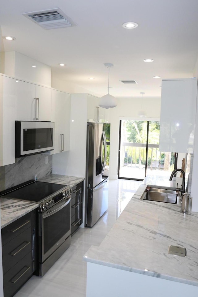 kitchen with visible vents, stainless steel appliances, hanging light fixtures, and white cabinetry