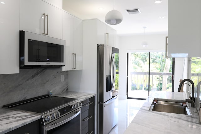 kitchen featuring stainless steel appliances, a sink, visible vents, white cabinetry, and decorative light fixtures