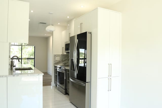 kitchen featuring white cabinets, modern cabinets, hanging light fixtures, stainless steel appliances, and a sink