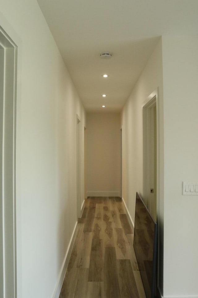 hallway featuring recessed lighting, baseboards, and wood finished floors