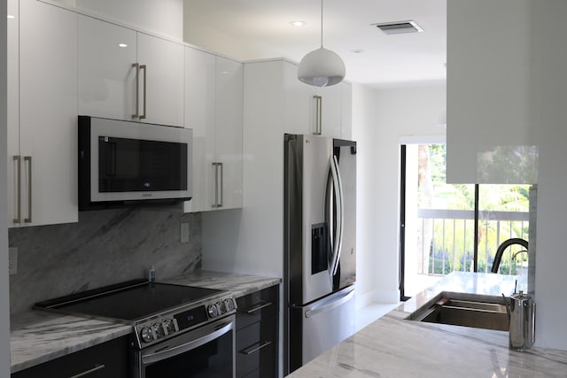 kitchen with modern cabinets, light stone countertops, stainless steel appliances, white cabinetry, and a sink