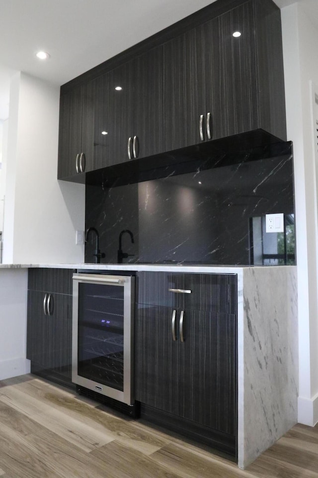 bar with light wood finished floors, wine cooler, and wet bar