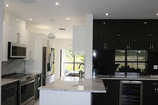 kitchen with decorative light fixtures, appliances with stainless steel finishes, white cabinetry, a sink, and beverage cooler