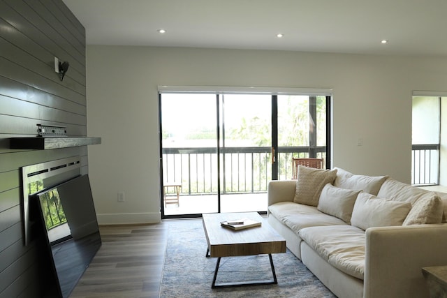 living area with baseboards, wooden walls, wood finished floors, and recessed lighting