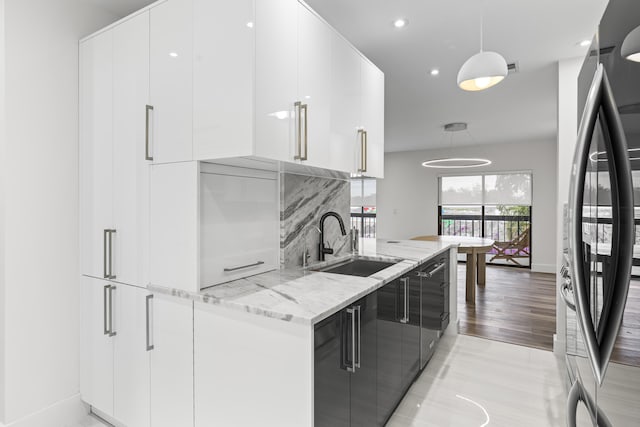 kitchen with refrigerator, hanging light fixtures, white cabinetry, a sink, and modern cabinets