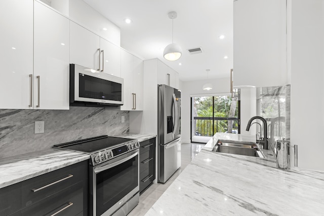 kitchen featuring pendant lighting, appliances with stainless steel finishes, white cabinetry, a sink, and modern cabinets