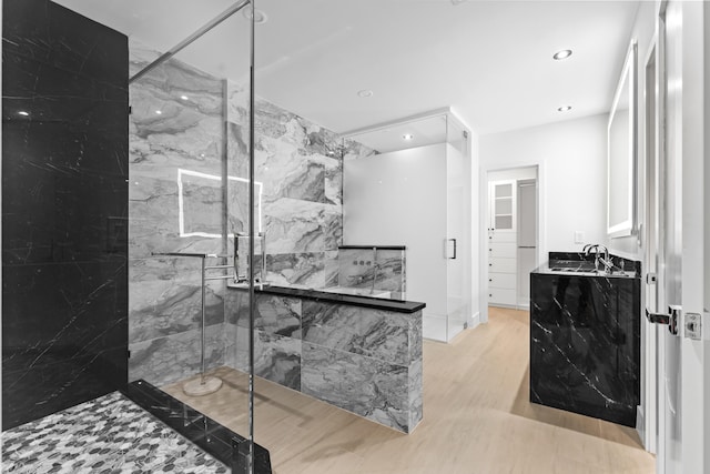 full bathroom featuring recessed lighting, vanity, a marble finish shower, and wood finished floors