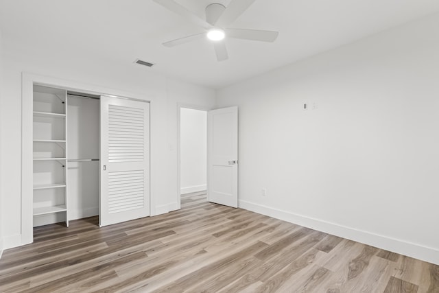 unfurnished bedroom with a closet, visible vents, ceiling fan, wood finished floors, and baseboards