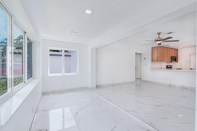 unfurnished living room featuring sink, ceiling fan, a healthy amount of sunlight, and light tile patterned floors