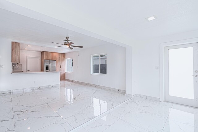 unfurnished living room with sink, light tile patterned flooring, and ceiling fan