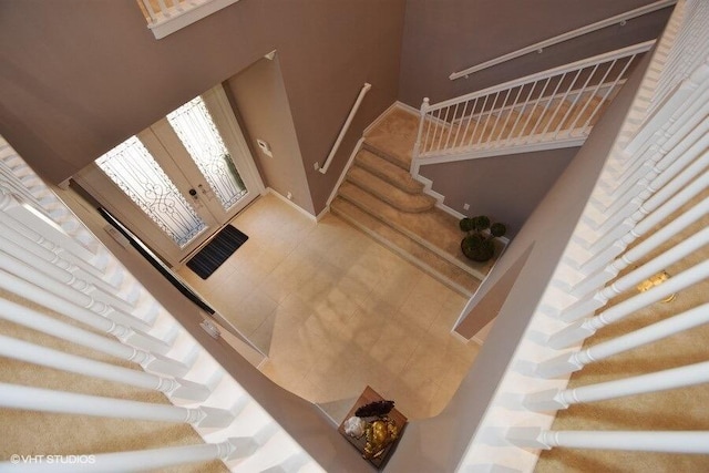 stairway with a towering ceiling and tile patterned floors