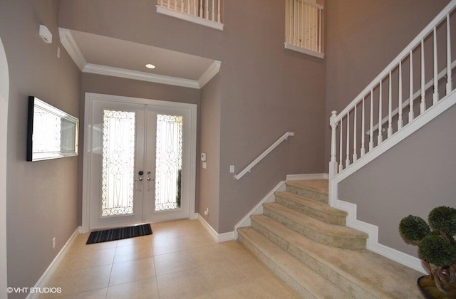 foyer entrance with tile patterned flooring, ornamental molding, and french doors