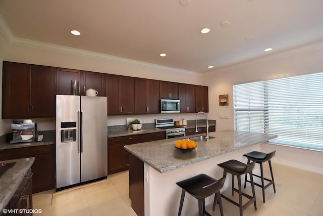 kitchen featuring a kitchen island with sink, a kitchen bar, light tile patterned floors, sink, and stainless steel appliances