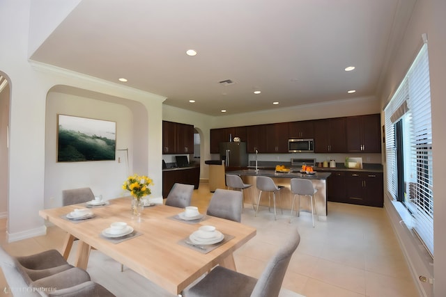 dining space with sink, crown molding, and light tile patterned flooring