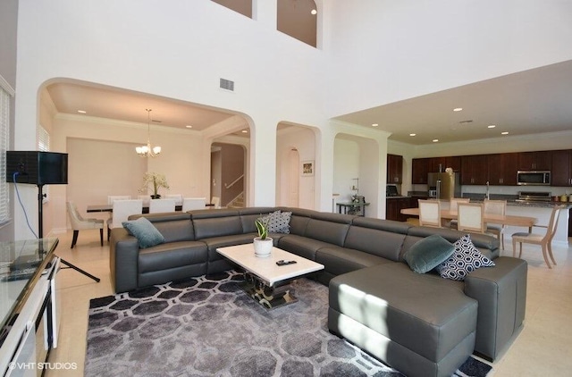 living room featuring a high ceiling, sink, crown molding, and a chandelier