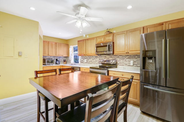 kitchen featuring tasteful backsplash, appliances with stainless steel finishes, light hardwood / wood-style floors, ceiling fan, and sink