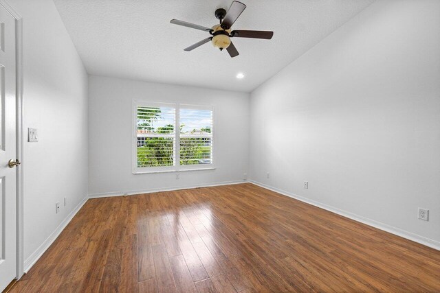 empty room with a textured ceiling, dark hardwood / wood-style floors, and ceiling fan