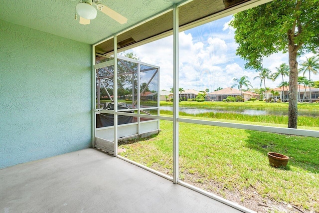 unfurnished sunroom featuring a water view and ceiling fan