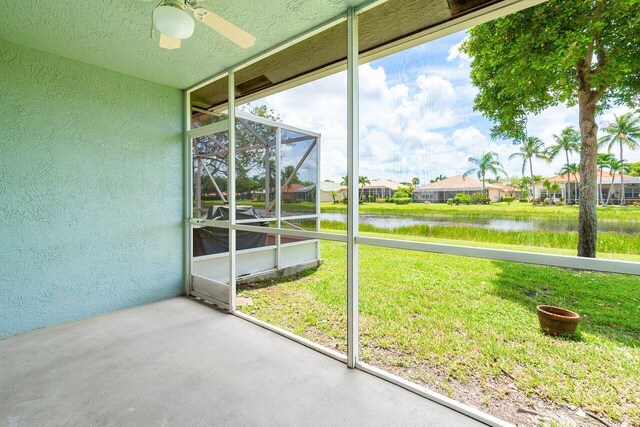 unfurnished sunroom with a water view and ceiling fan