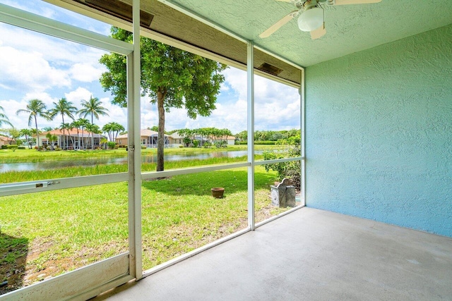 unfurnished sunroom with ceiling fan and a water view