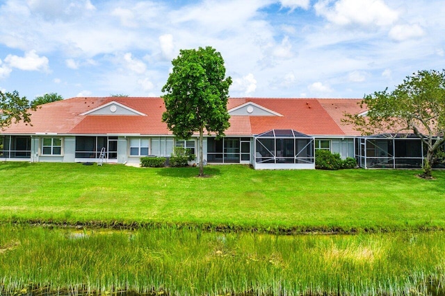 rear view of house featuring a lanai and a lawn