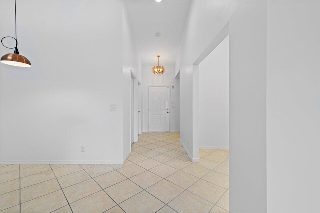 hallway with light tile patterned flooring and a notable chandelier