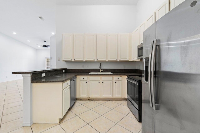 kitchen featuring sink, appliances with stainless steel finishes, cream cabinets, light tile patterned flooring, and kitchen peninsula