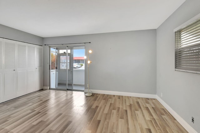 unfurnished bedroom with light hardwood / wood-style floors, multiple windows, and a closet