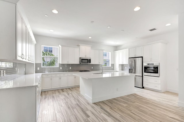 kitchen featuring light hardwood / wood-style flooring, appliances with stainless steel finishes, a kitchen island with sink, and sink