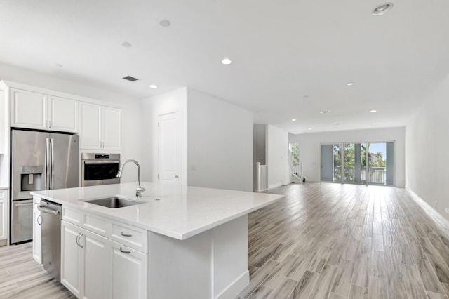 kitchen with a center island with sink, appliances with stainless steel finishes, sink, and white cabinets