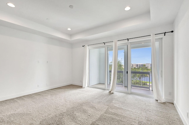 carpeted empty room with a tray ceiling