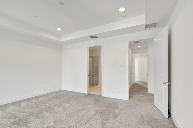 unfurnished bedroom featuring ensuite bath and light colored carpet