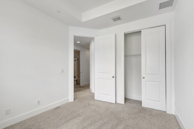 unfurnished bedroom with light colored carpet and a closet