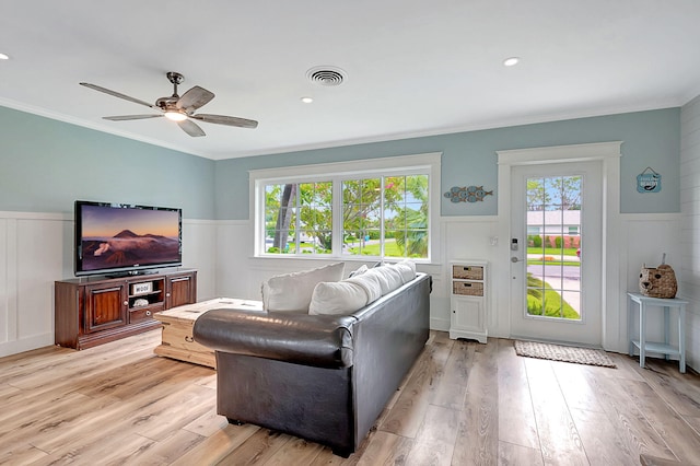 living room featuring visible vents, ornamental molding, ceiling fan, light wood-style floors, and wainscoting